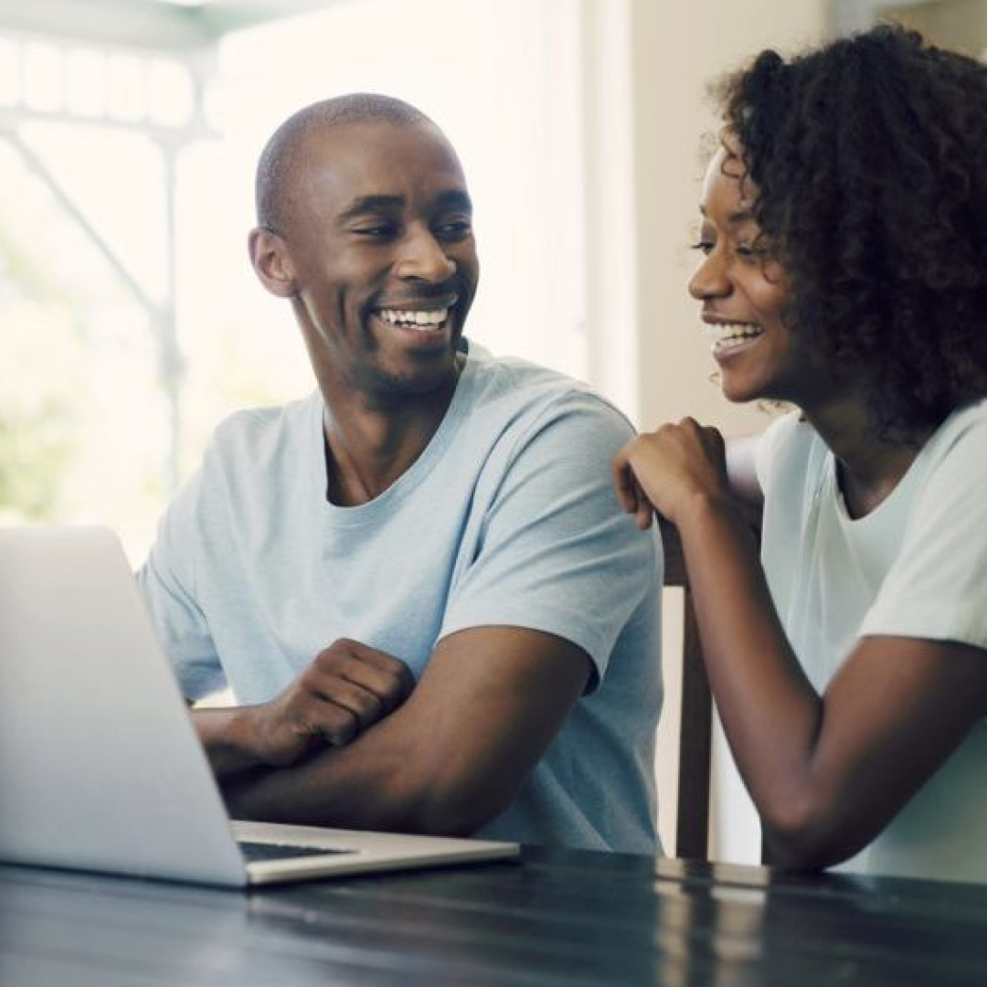 Man and woman laughing and looking at computer